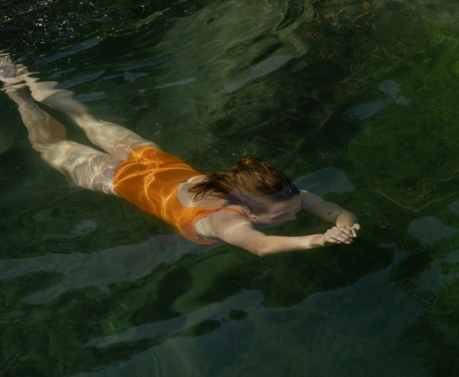 Woman swimming underwater in open water, arms extended